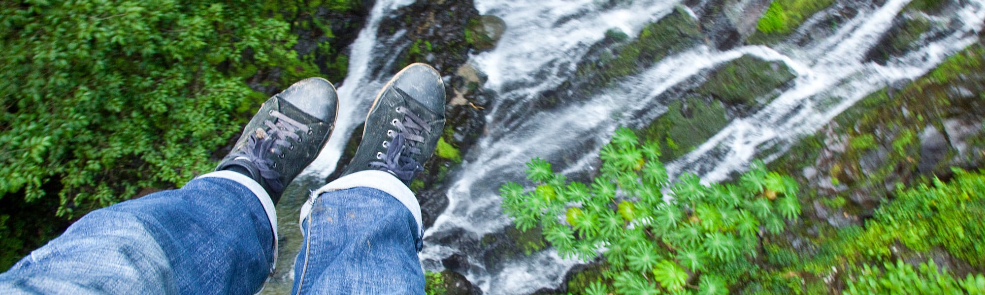 Close up of person's feet riding biplane over waterfall